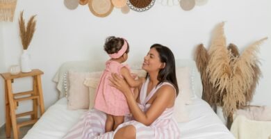 a woman sitting on a bed holding a little girl